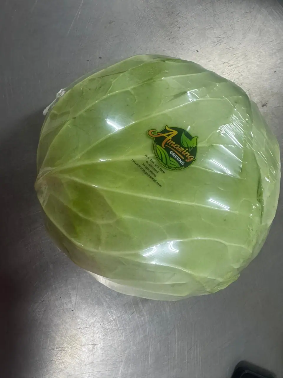 Whole cabbage shrink-wrapped with the Amazing Greens label